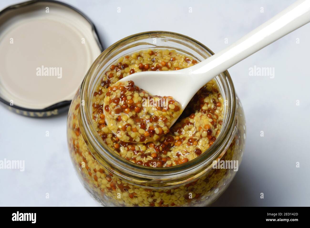 Coarsegrained mustard in glass with spoon, Dijon mustard, France Stock