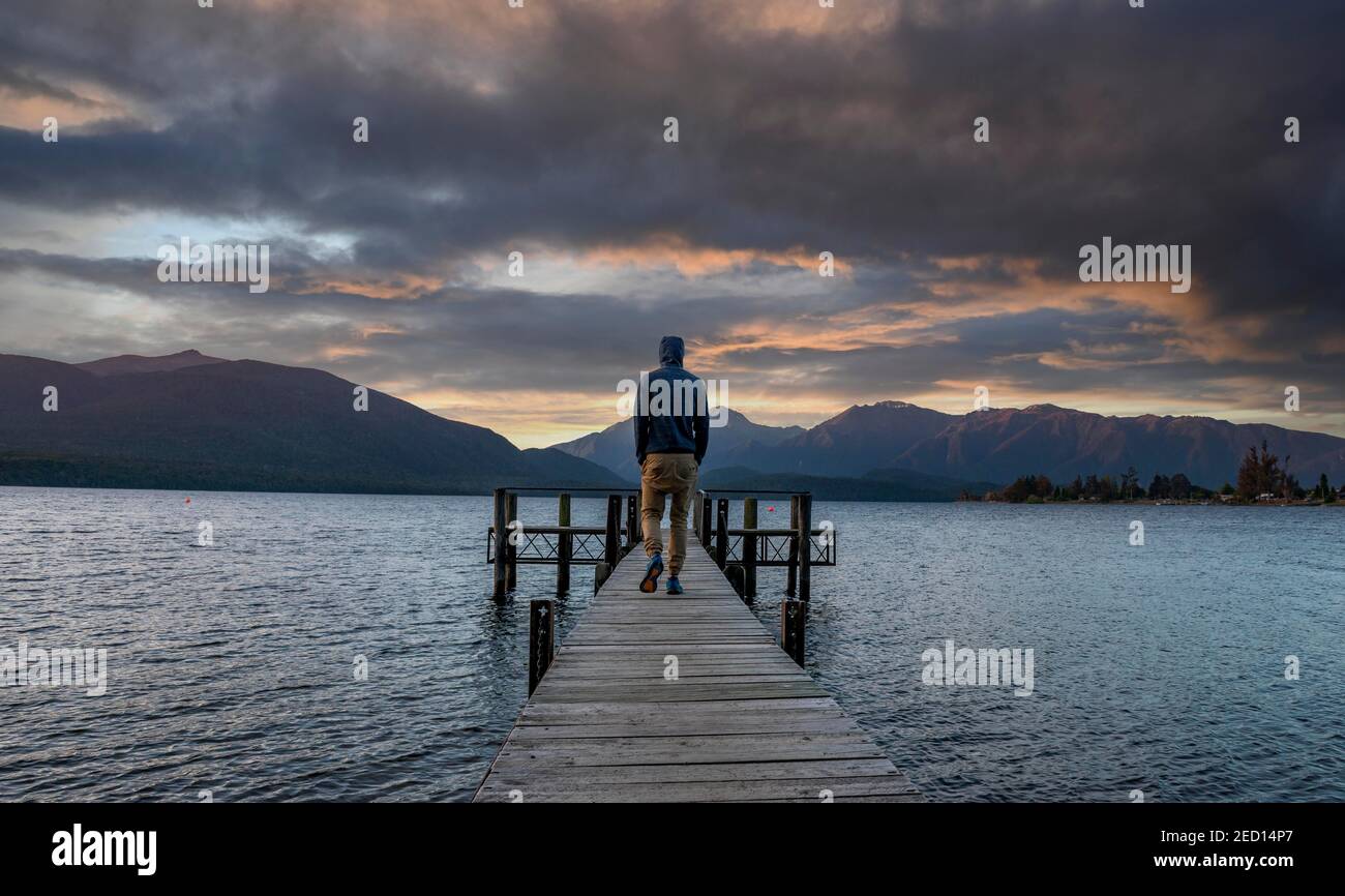 Juger man on jetty at lake, Lake Te Anau at sunset, Te Anau, South Island, New Zealand Stock Photo