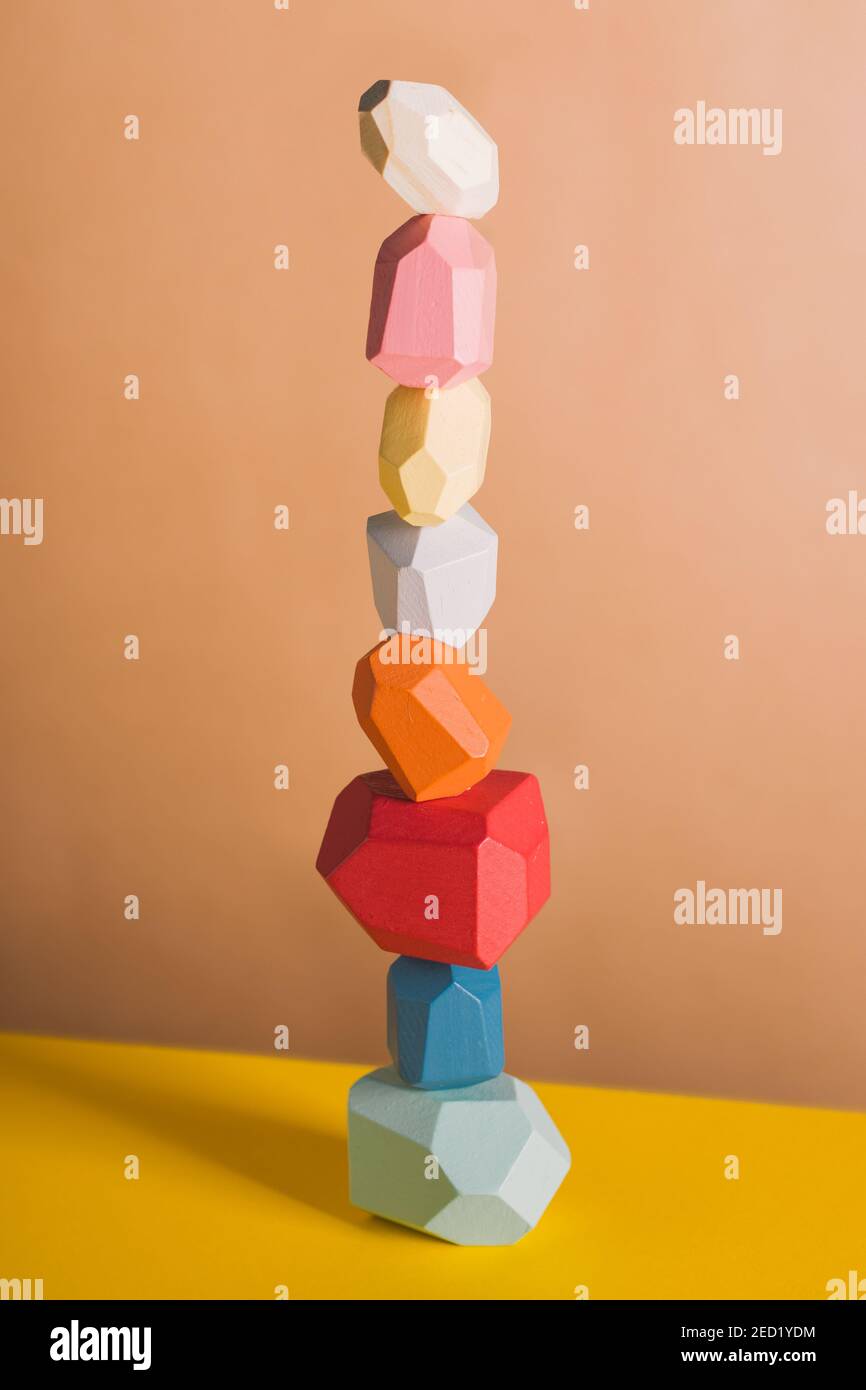 Wooden blocks in shapes of gems of various colors stacked on beige background in studio Stock