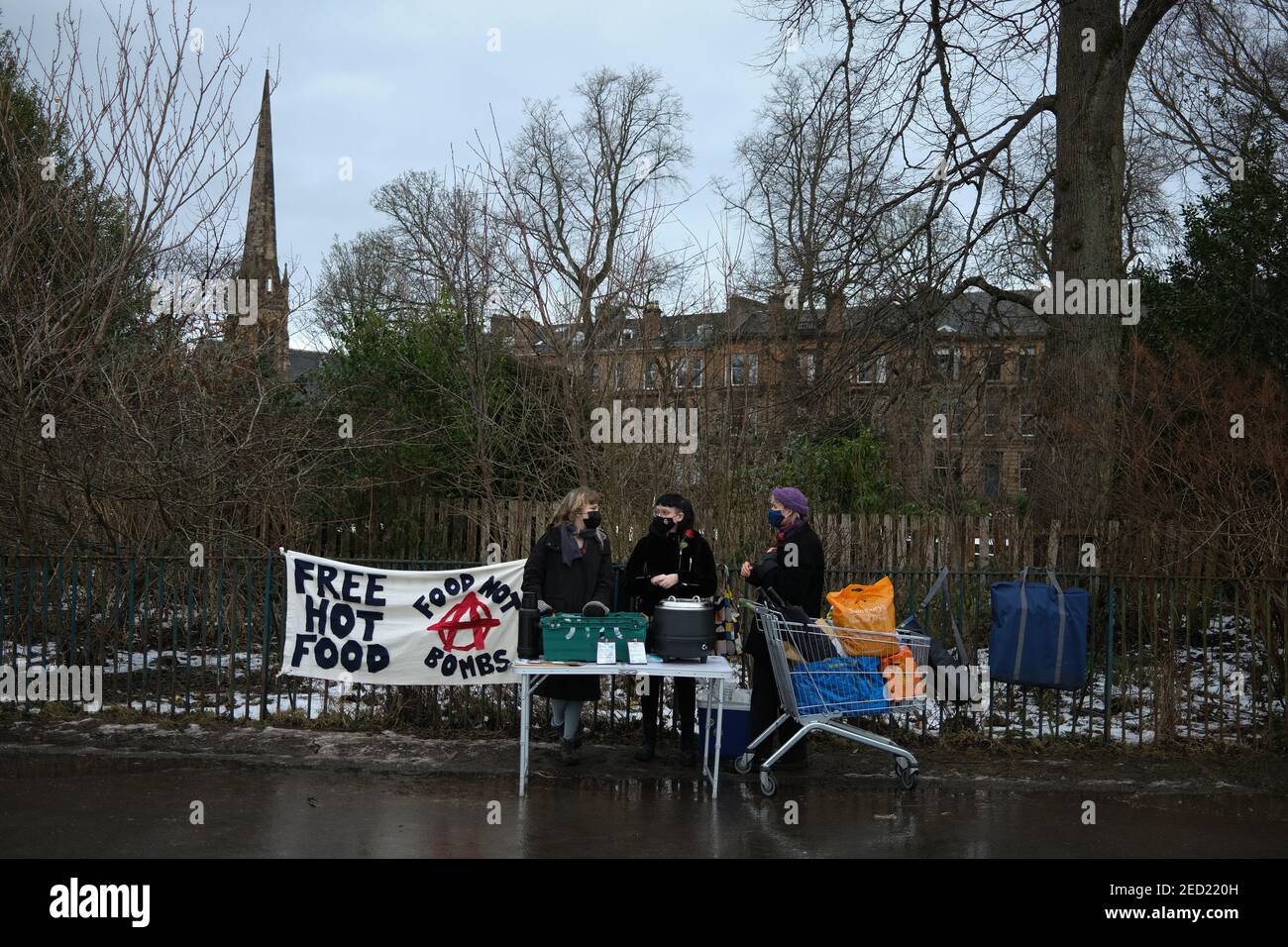 Glasgow, UK, on 14 February 2021. Three volunteers for 'Food Not Bombs (Glasgow)' organisation hand out hot soup and vegan haggis, in Queen's Park. This is the 4th weekend of the stall providing food, donated by local companies, to anyone who requests it, and clothes to those in need, in the city's Southside during the current CoronaVirus Covid-19 health pandemic. Photo credit: Jeremy Sutton-Hibbert/ Alamy Live News. Stock Photo