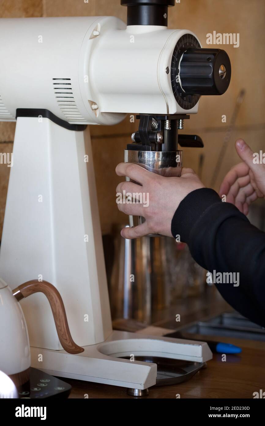 barista hands grinding coffee with white mahlkonig ek 43 grinder in coffee shop, closeup, no people Stock Photo