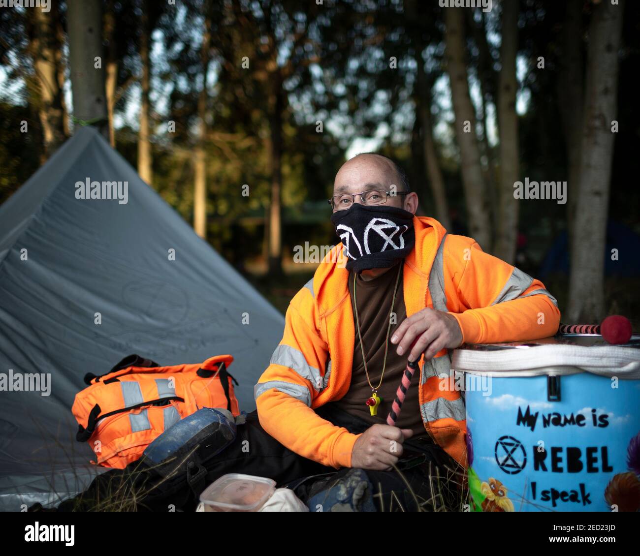 A male activist from Extinction Rebellion sits outside his tent with his drums at a campsite in Brockwell Park, London, 31 August 2020 Stock Photo