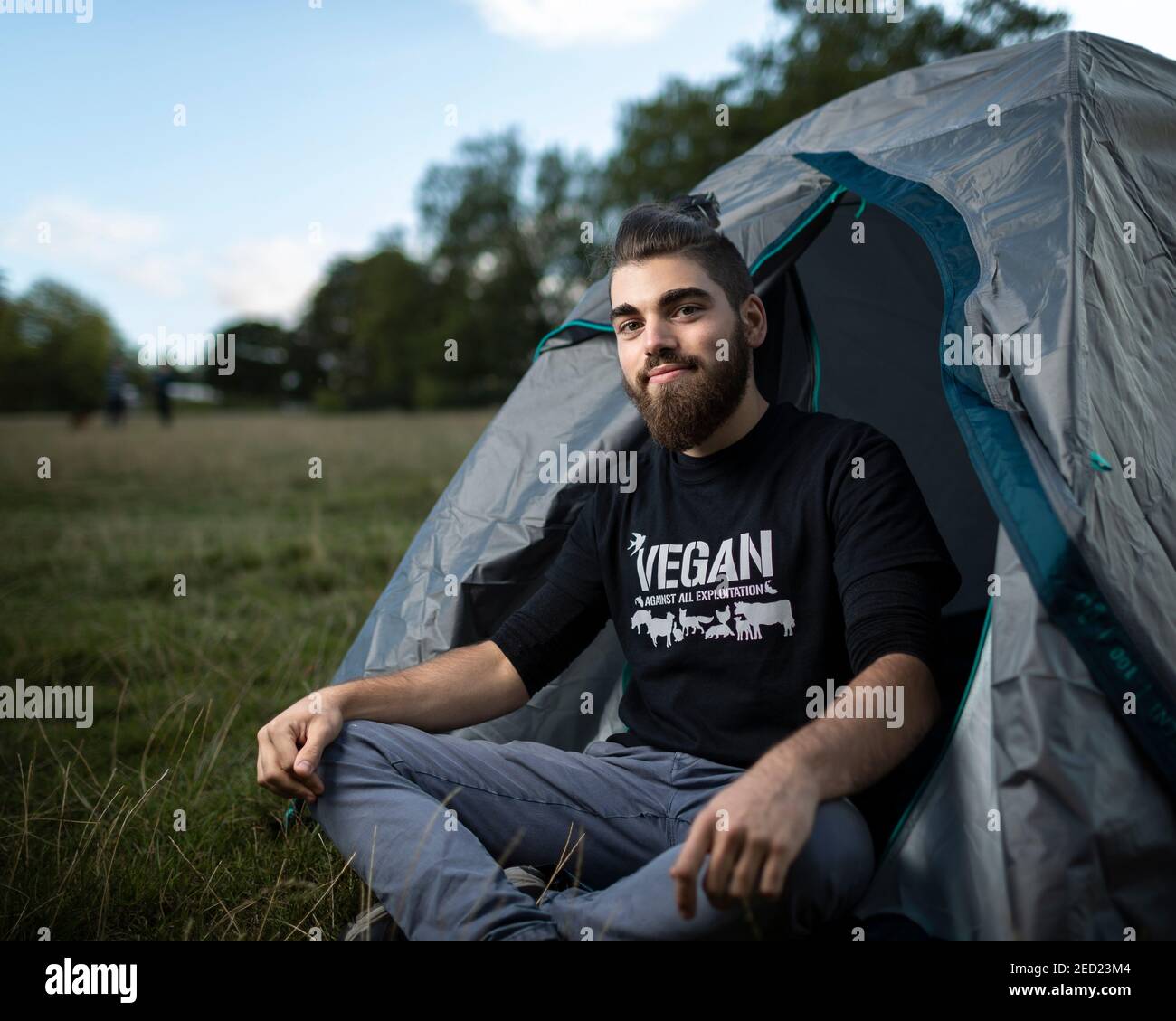 A male activist from Animal Rebellion sits at the entrance of his tent at a campsite in Brockwell Park, London, 31 August 2020 Stock Photo