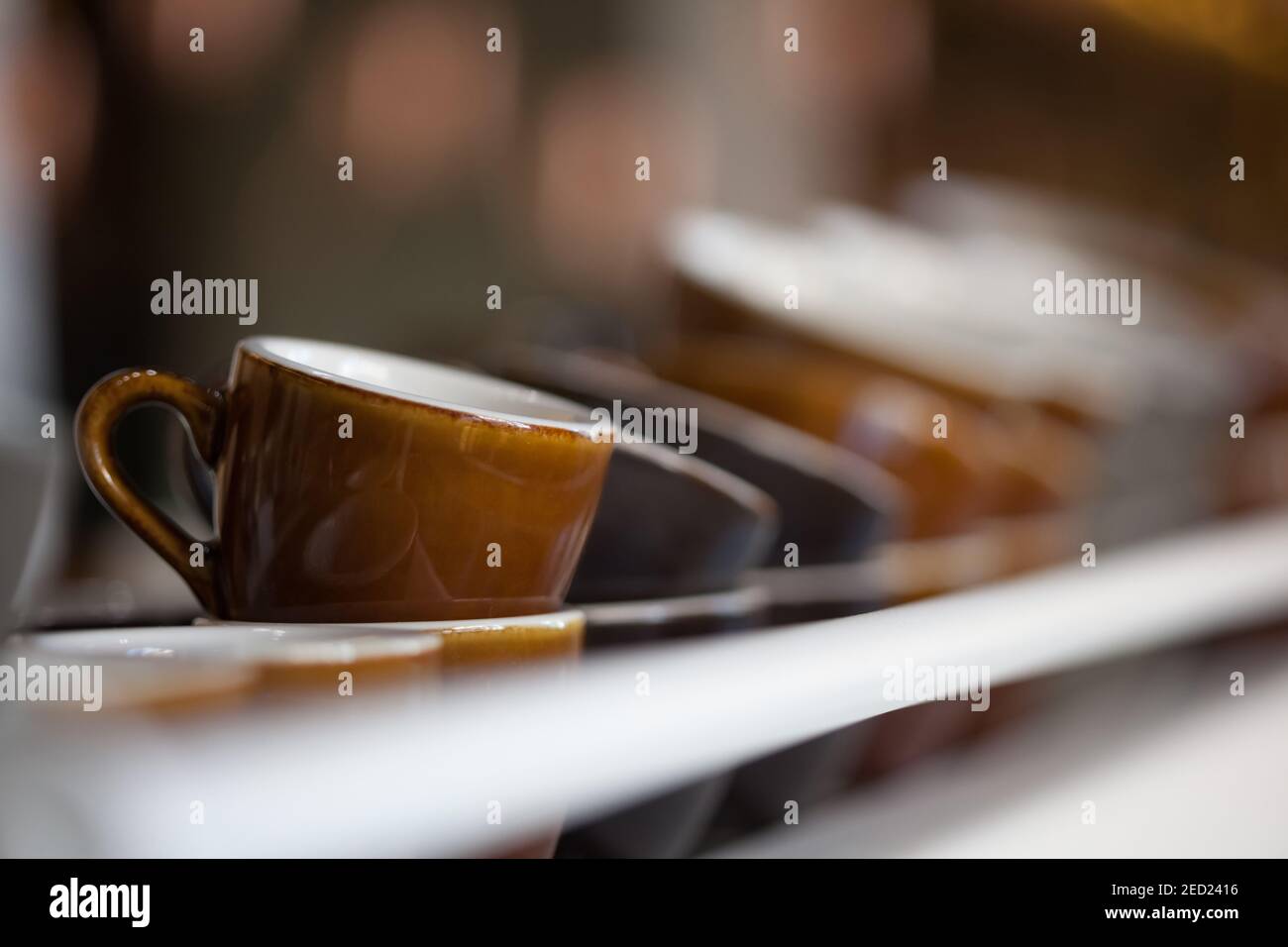 bunch of brown ceramic coffee cups on top of espresso machine, blurred background, horizontal, no people Stock Photo