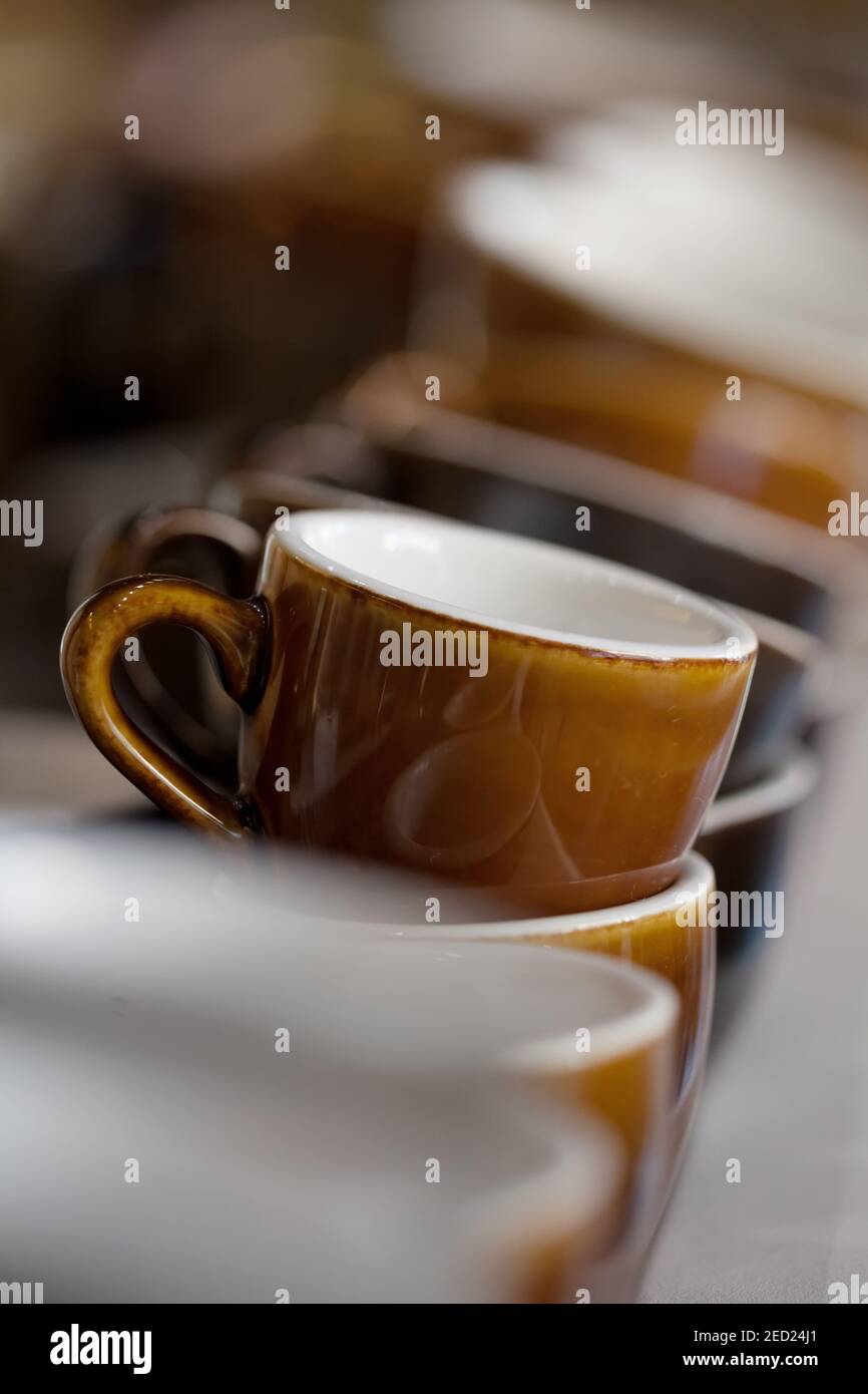 bunch of brown Loveramics ceramic coffee cups on top of espresso machine, blurred background, vertical, no people Stock Photo