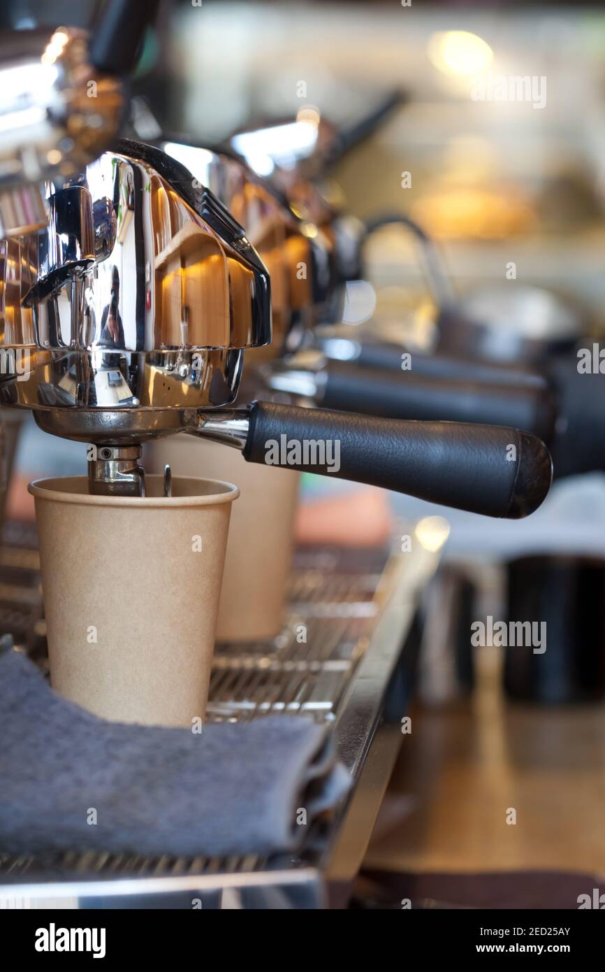 modern professional espresso machine in coffee shop with coffee pouring into take away paper cup, nobody Stock Photo
