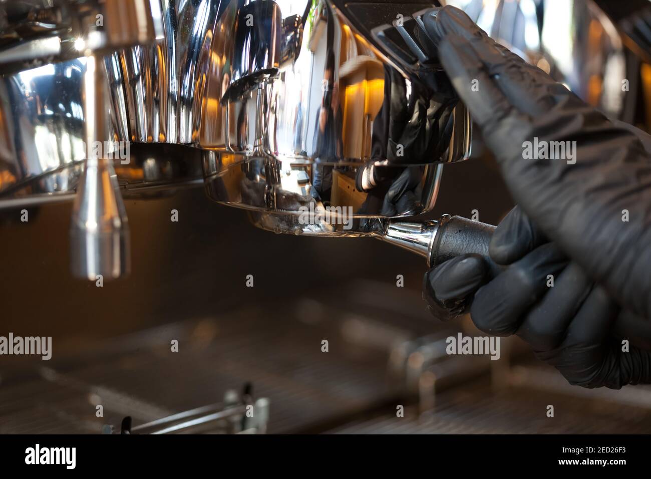 barista hands inserting bottomless holder into professional espresso coffee machine, closeup Stock Photo