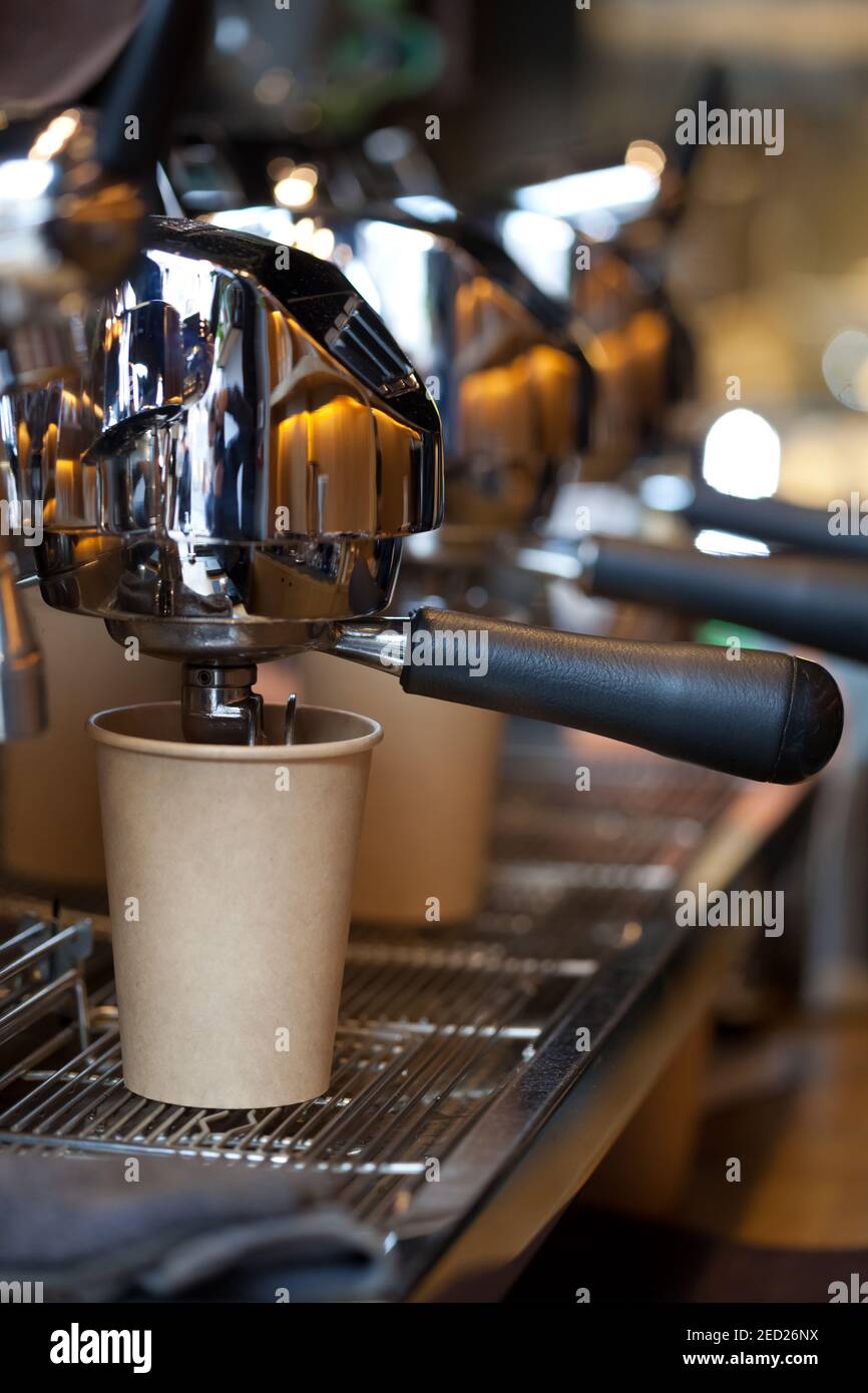 modern professional espresso machine in coffee shop with coffee pouring into take away paper cup, nobody Stock Photo