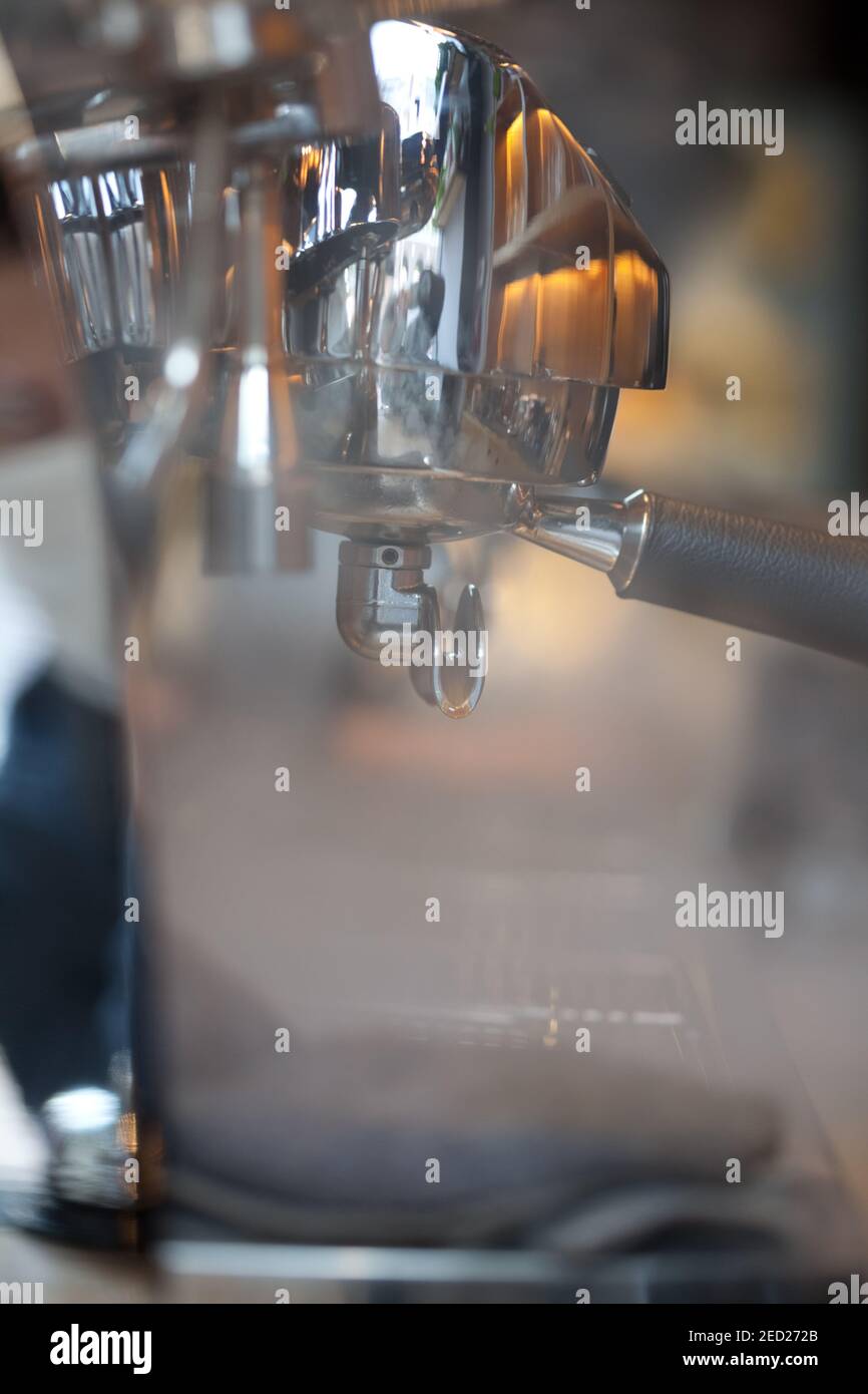 closeup of holders and steam in professional Victoria Arduino group head espresso coffee machine, blurred background, no people Stock Photo