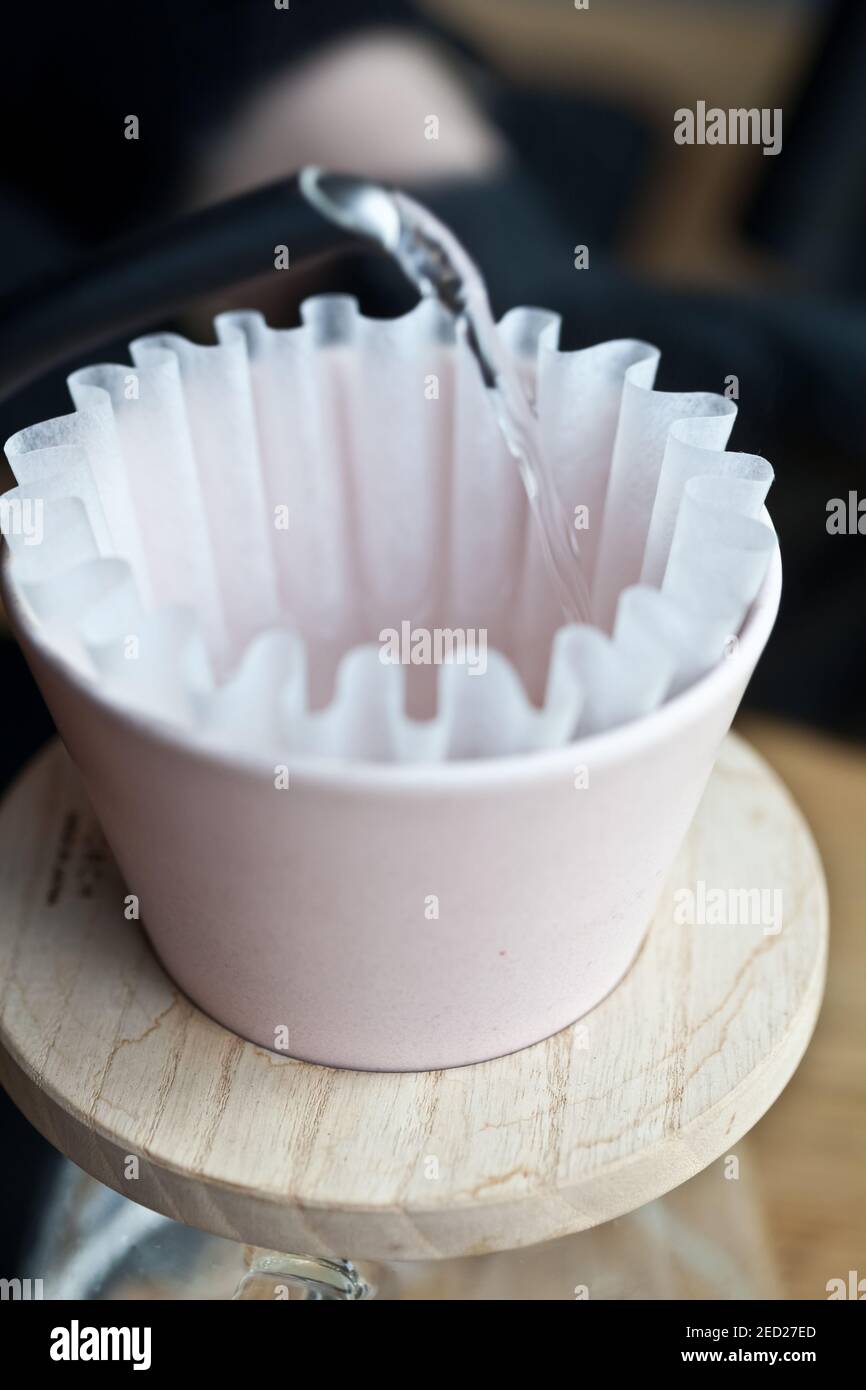 closeup of kettle pouring hot water into pour over paper filter during coffee brewing preparation Stock Photo