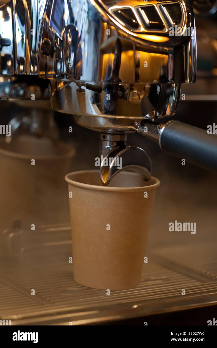 closeup of coffee pouring from spouts into take away paper cup in
