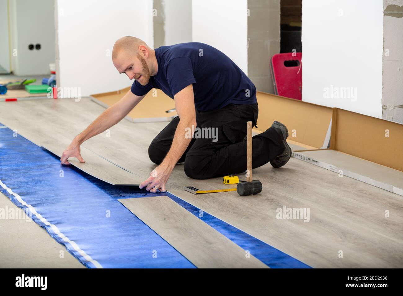 Worker joining click lock vinyl floor plank covering at home renovation