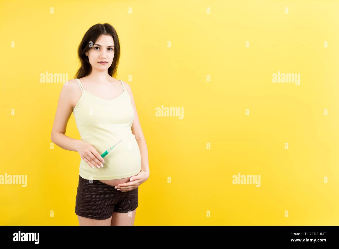 syringe for injection in pregnant woman's hand at colorful background
