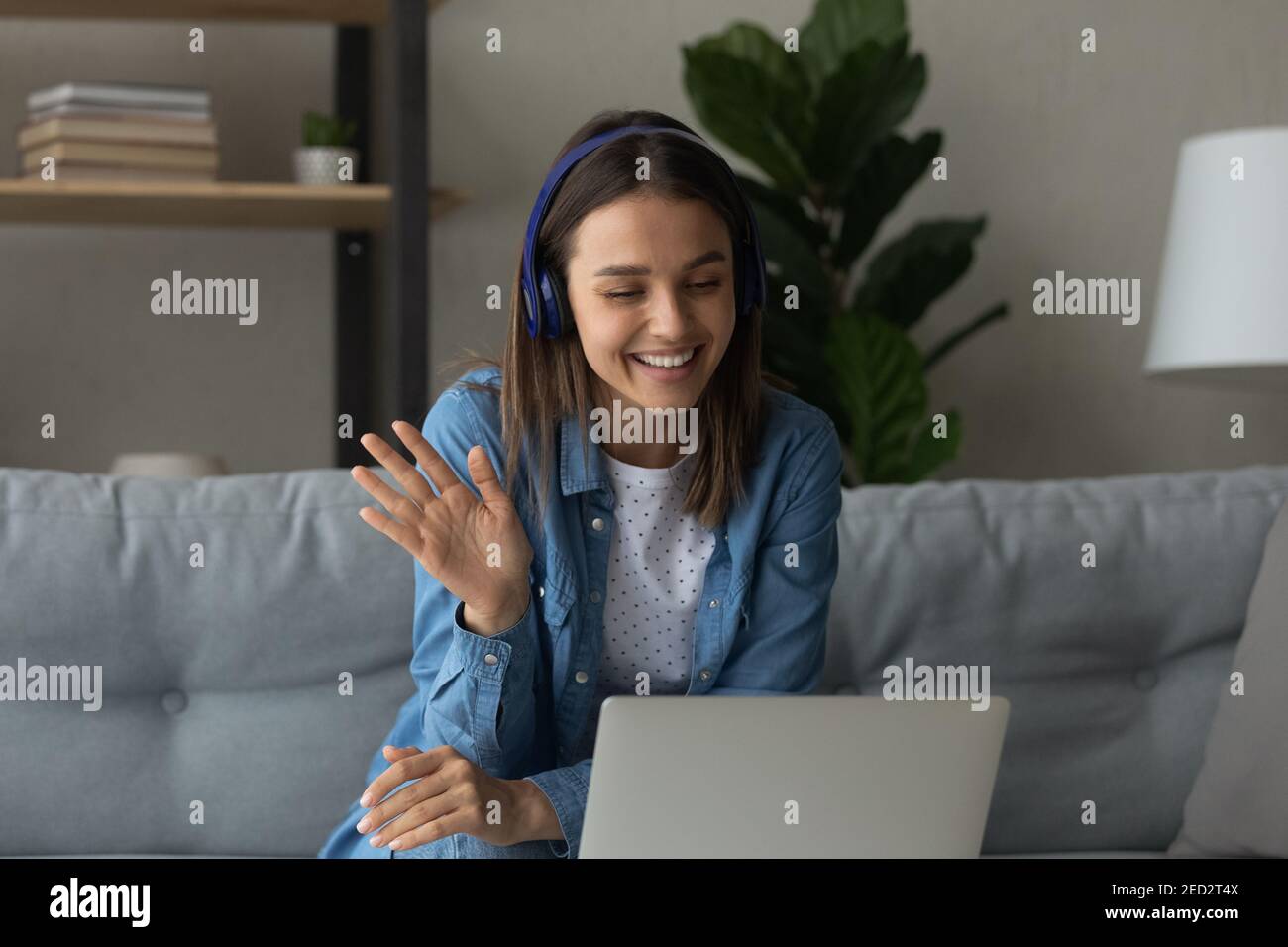 Happy young woman in headphones say hi making video call Stock Photo