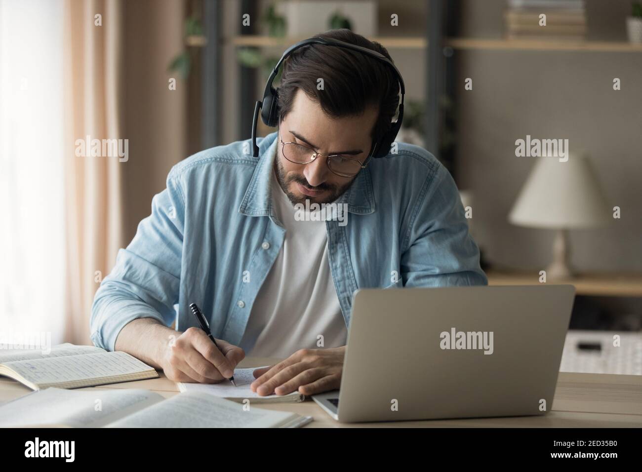 Millennial man focused on remote work make translation using laptop Stock Photo