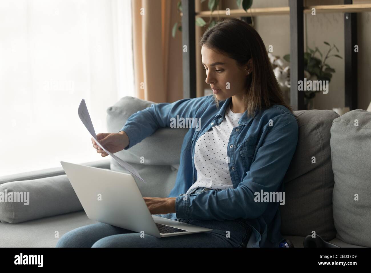 Young female read paper letter check information online using laptop Stock Photo