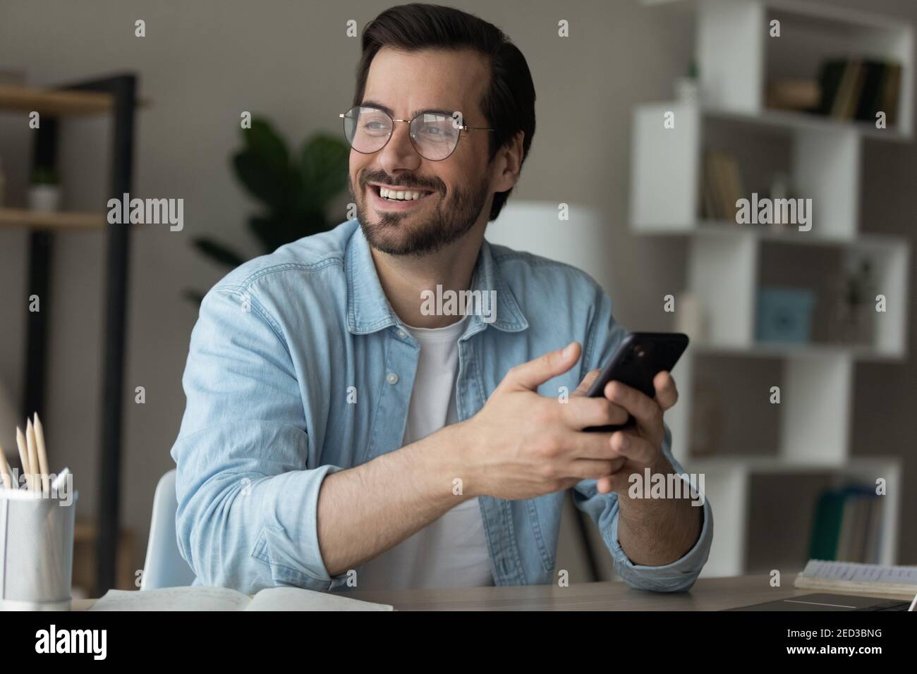 Young man holding cell look away excited with new opportunity Stock Photo