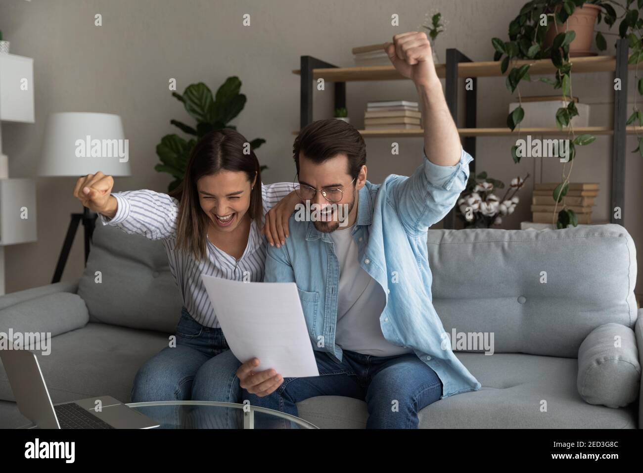 Excited young married couple getting money grant for family business Stock Photo