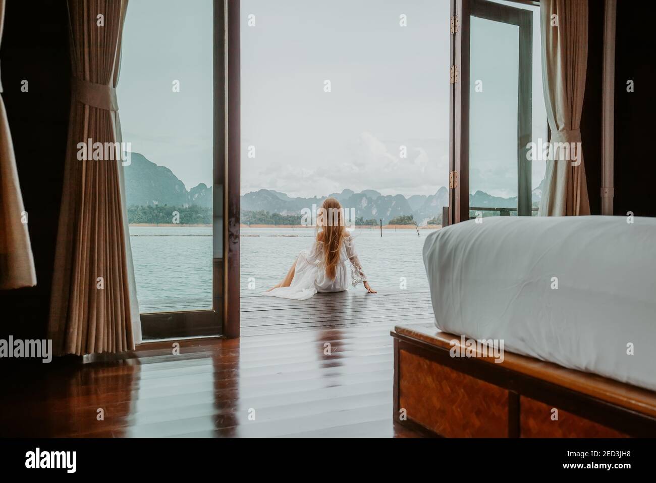 Travel Woman in White Dress Sitting Outdoor near Wooden House on Water ...