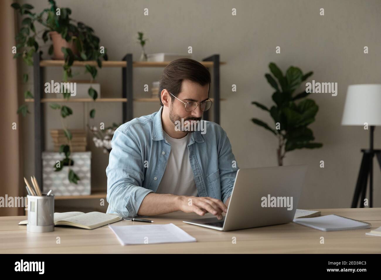 Focused young businessman freelancer engaged in distant work on laptop Stock Photo