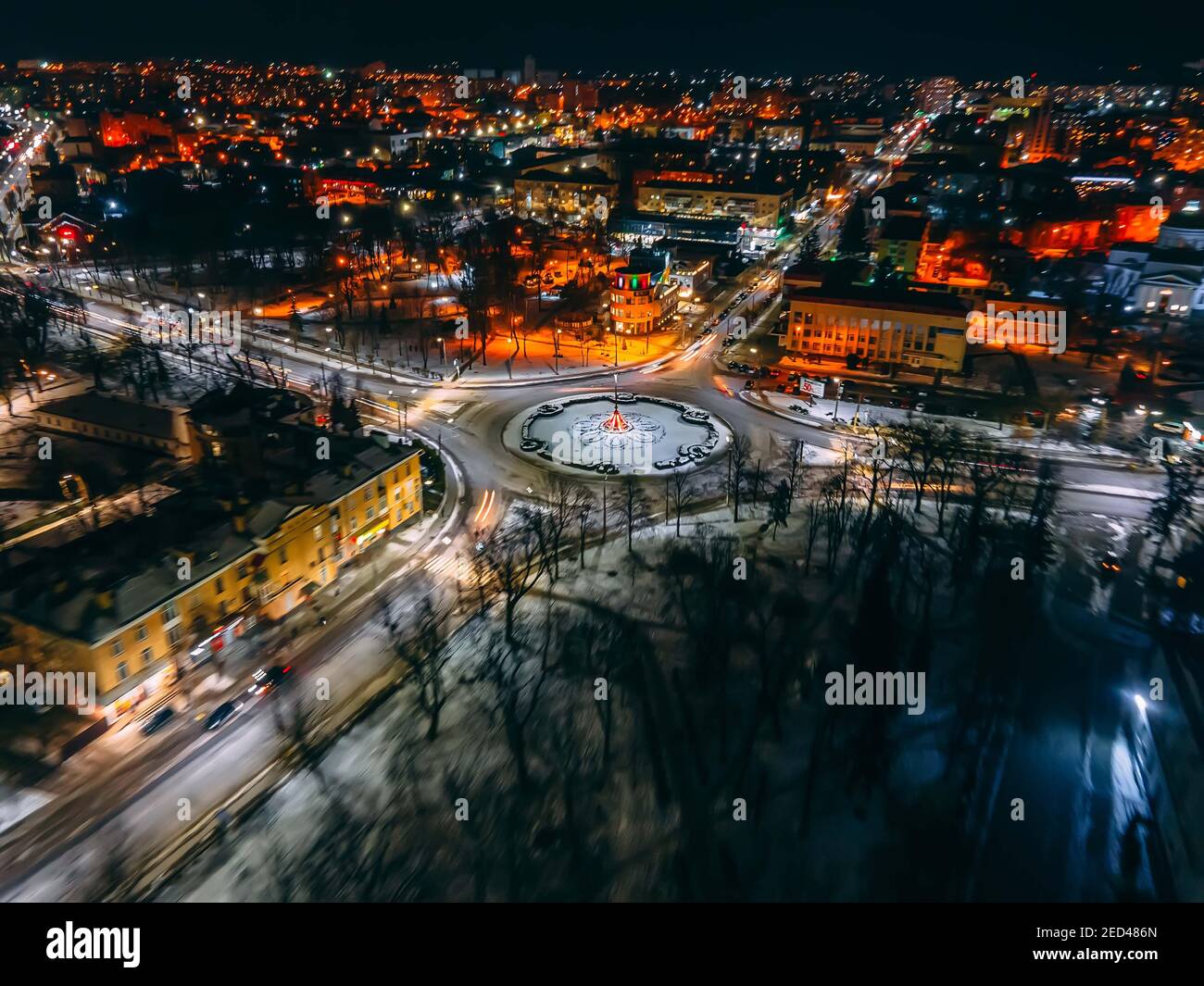 Aerial view of roundabout road with circular cars in small european city at winter night, long exposure. Kyiv region, Ukraine Stock Photo