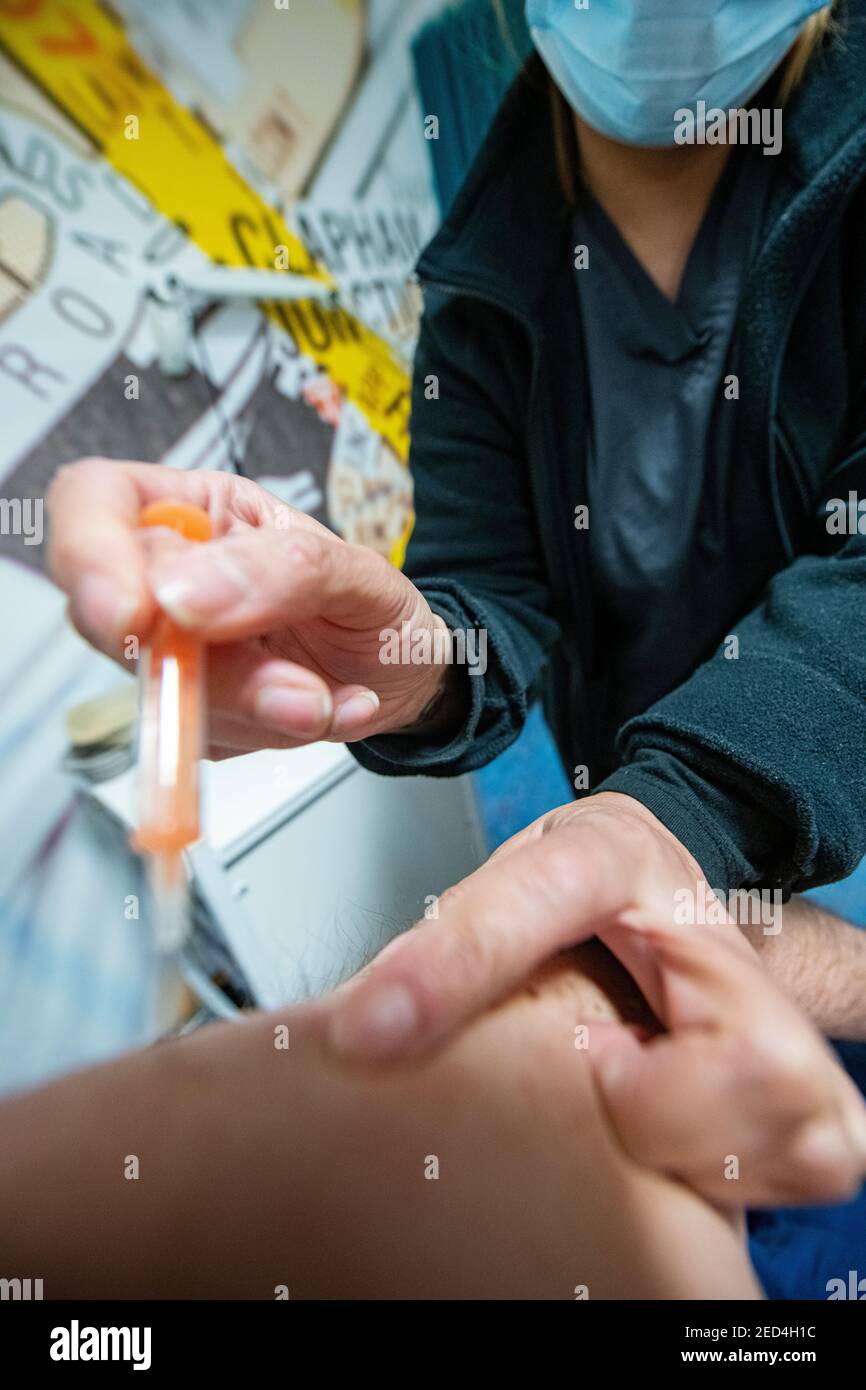 A needle is insrted into an arm by a health worker containing the Astra Zeneca  COVID-19 vaccine in 2021 Stock Photo