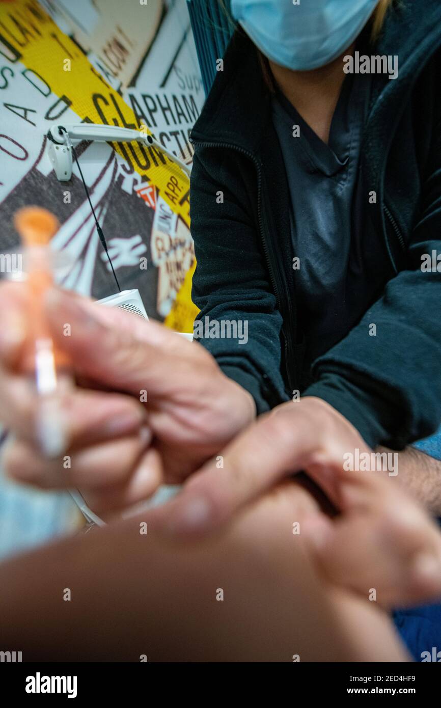 A needle is insrted into an arm by a health worker containing the Astra Zeneca  COVID-19 vaccine in 2021 Stock Photo