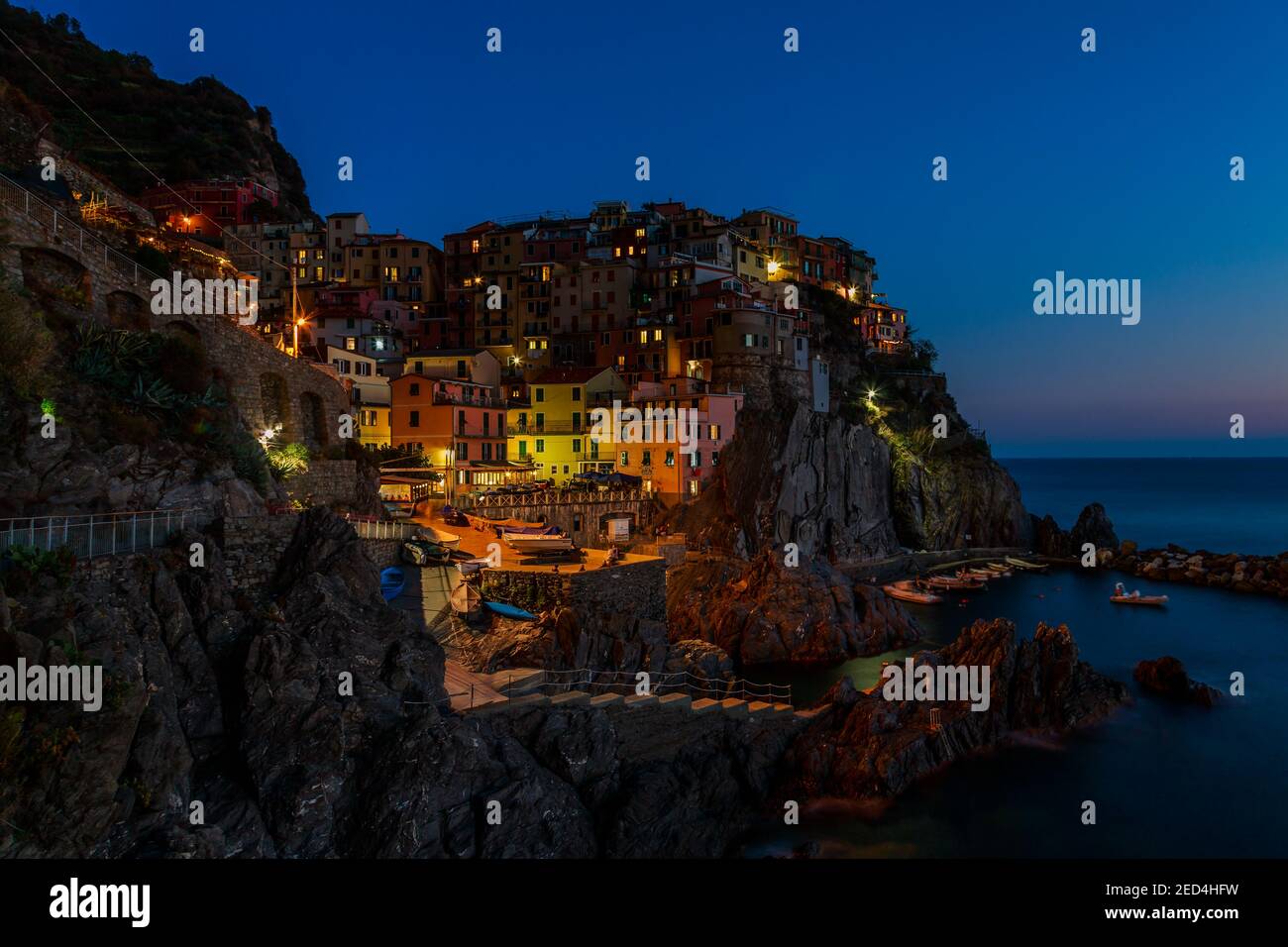 Looking over and down on a very colorful night in the rocky Italian seacoast village and historic waterfront of Manarola, Cinque Terre, Italy Stock Photo