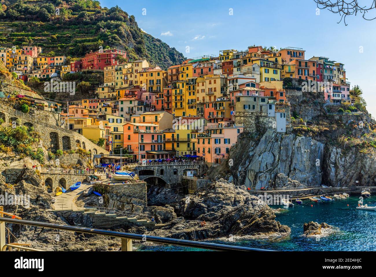 A bright seacoast afternoon light bathes the many colors of the houses in the Cinque Terre village of Manarola, with a view of its historic waterfront. Stock Photo