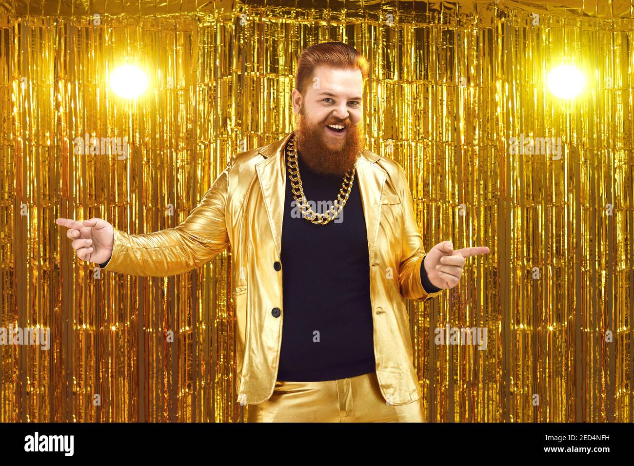 Uninhibited bearded man in shiny golden suit dancing and having fun at disco party Stock Photo