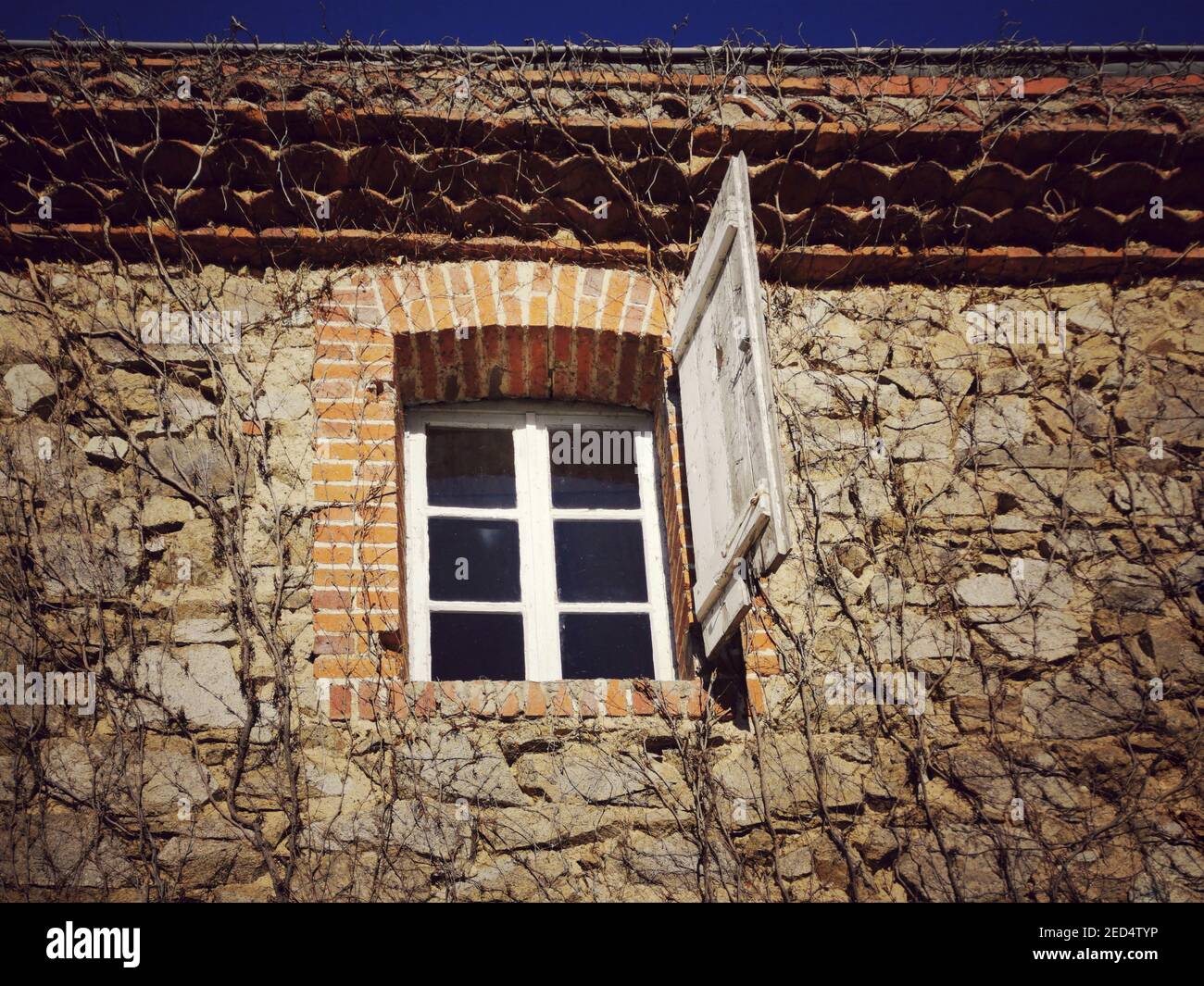 A low angle shot of an old stone building with an open window covered ...