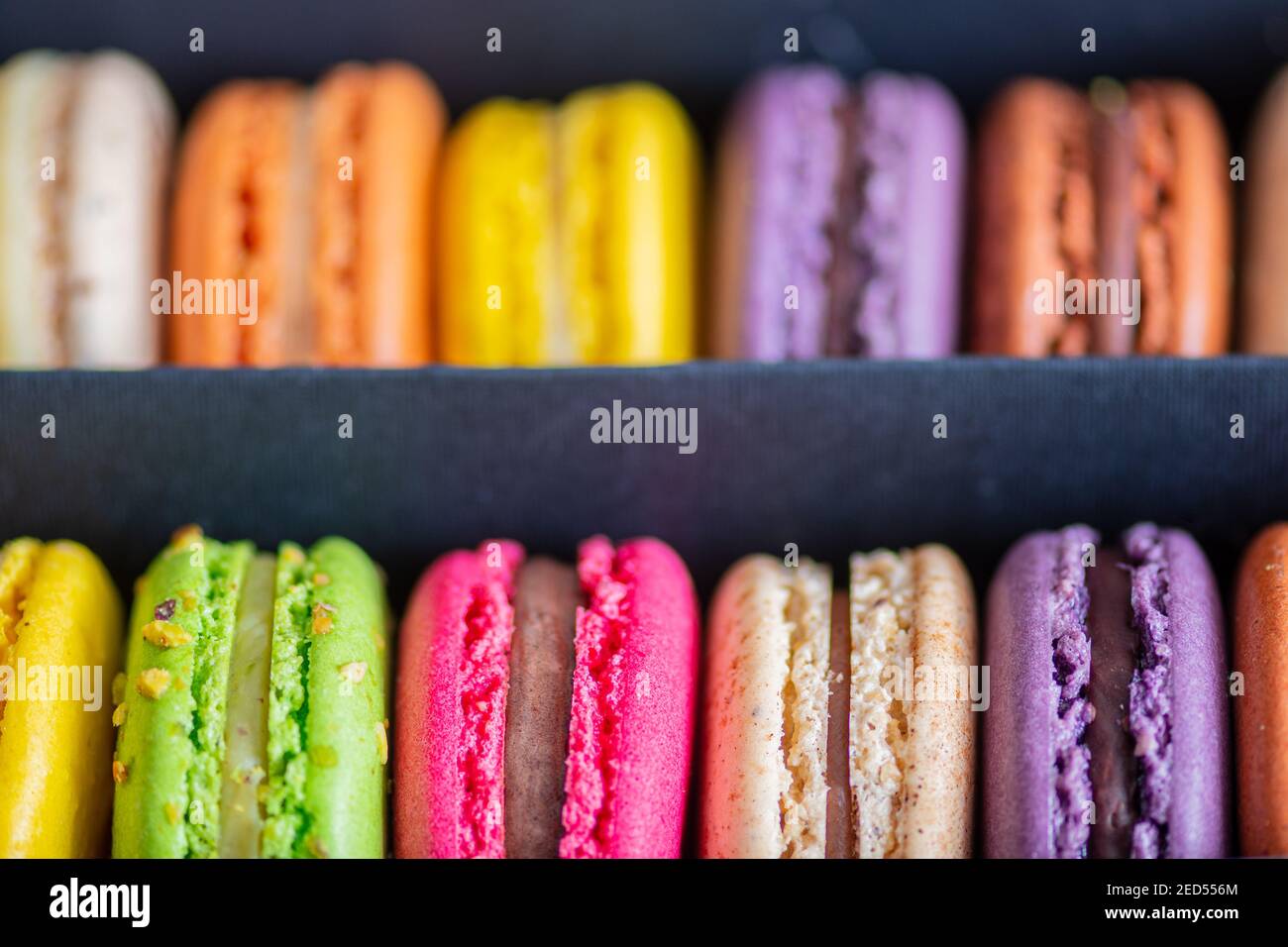 Various colorful macarons or French macaroons in a row in a gift box, sweet meringue-based confection made with egg white, icing sugar, granulated Stock Photo