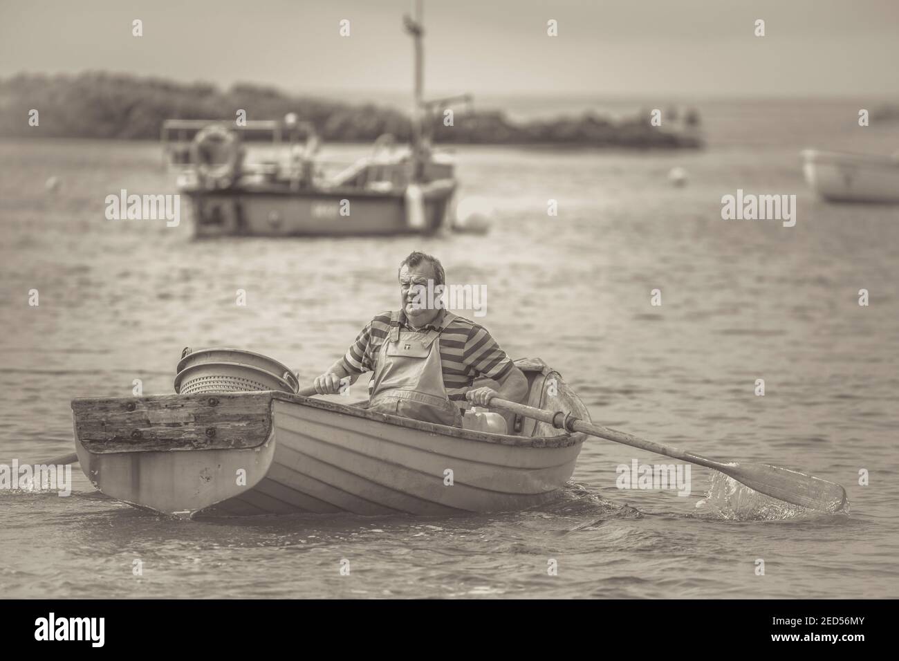 Mono UK fisherman isolated in his rowing boat, rowing out to sea. Stock Photo