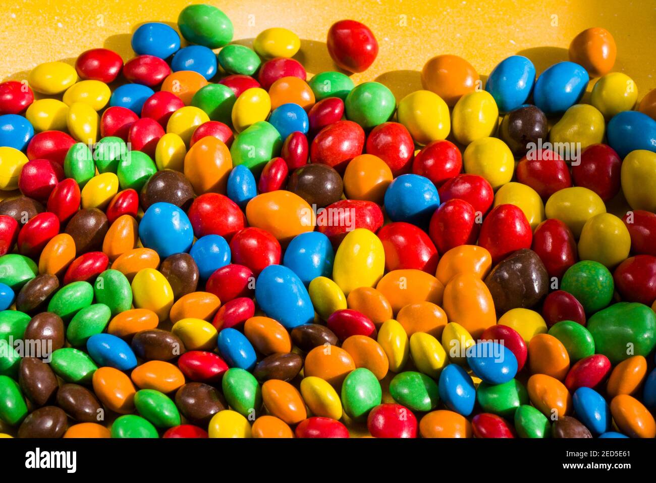 M&M's candy on the yellow background, colorful candy and multicolored ...