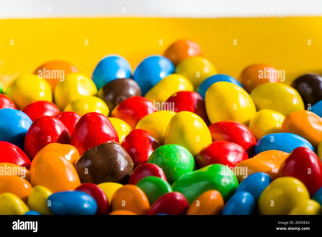 M&M's candy on the yellow background, colorful candy and multicolored ...