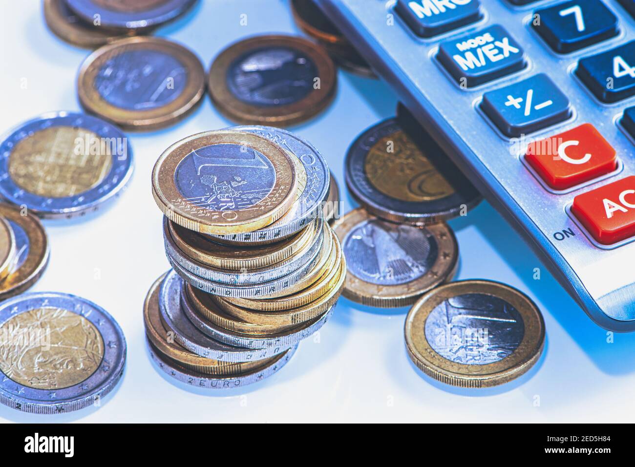 stack of one and two Euro coins beside a calculator Stock Photo - Alamy