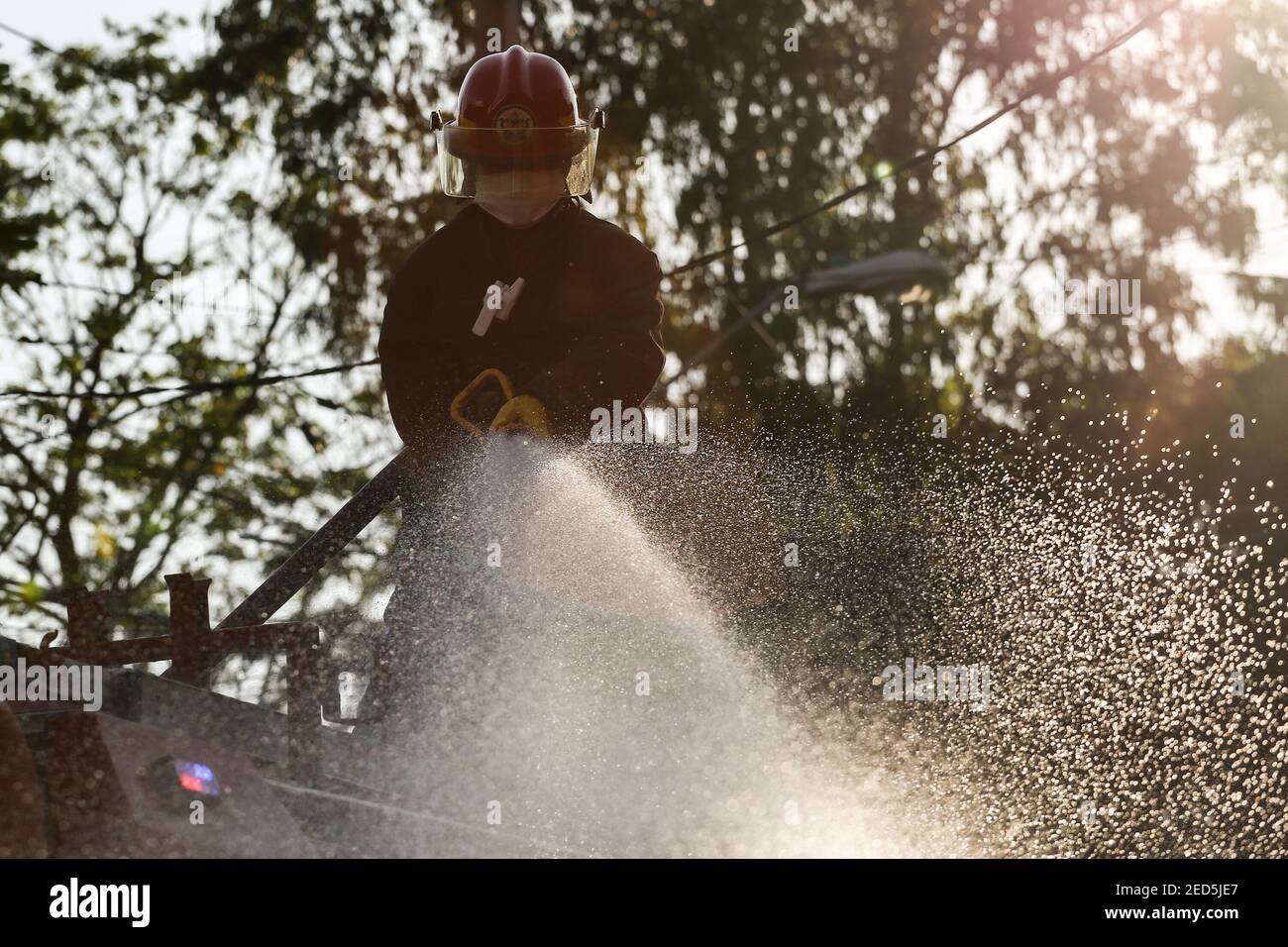 Fireman uses a hoses to spray disinfectant solution along a street to help curb the spread of COVID-19 during the coronavirus lockdown in Manila, Philippines. Stock Photo