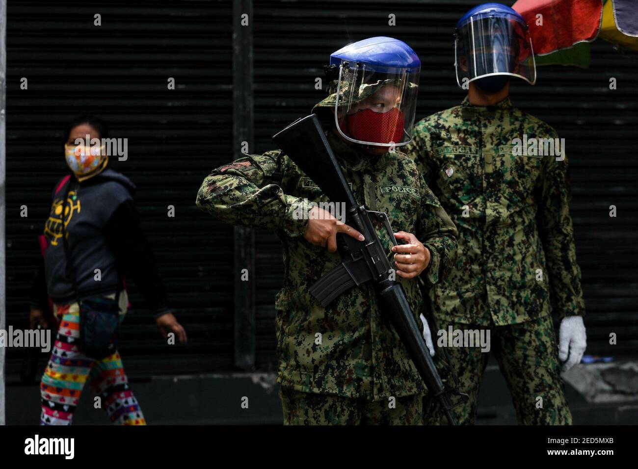 Policemen wearing protective face shields and masks stop and inspect entering vehicles at a checkpoint  during community quarantine in Manila, Philippines. Stock Photo