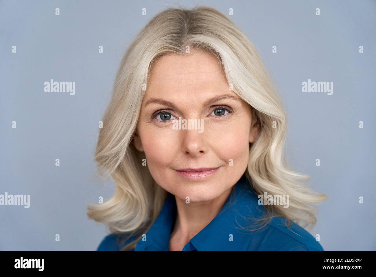 Confident mid aged business woman looking at camera isolated on grey, headshot. Stock Photo