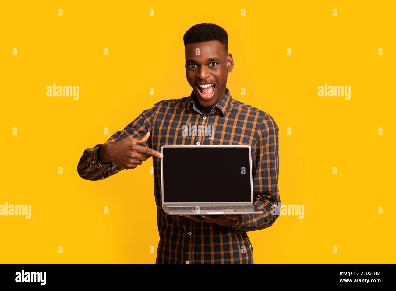 Check This Website. African Guy Pointing At Laptop Computer With Black Screen Stock Photo