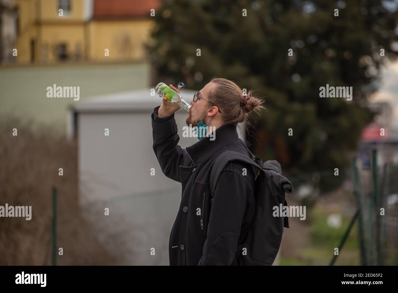 Prague, Czech Republic. 02-13-2021. Young trendy young man is drinking a soda while walking in the city center of Prague during a cold winter day. Stock Photo