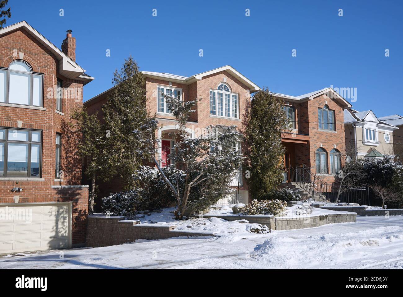 Street with large modern suburban detached middle class single family houses on a sunny day in winter Stock Photo