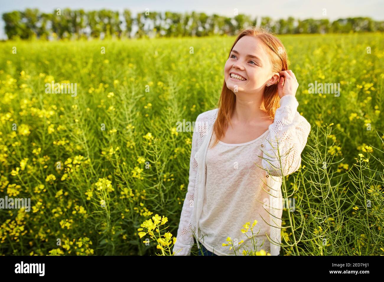 Redhead girl in a rapeseed field, on a sunny day Stock Photo - Alamy
