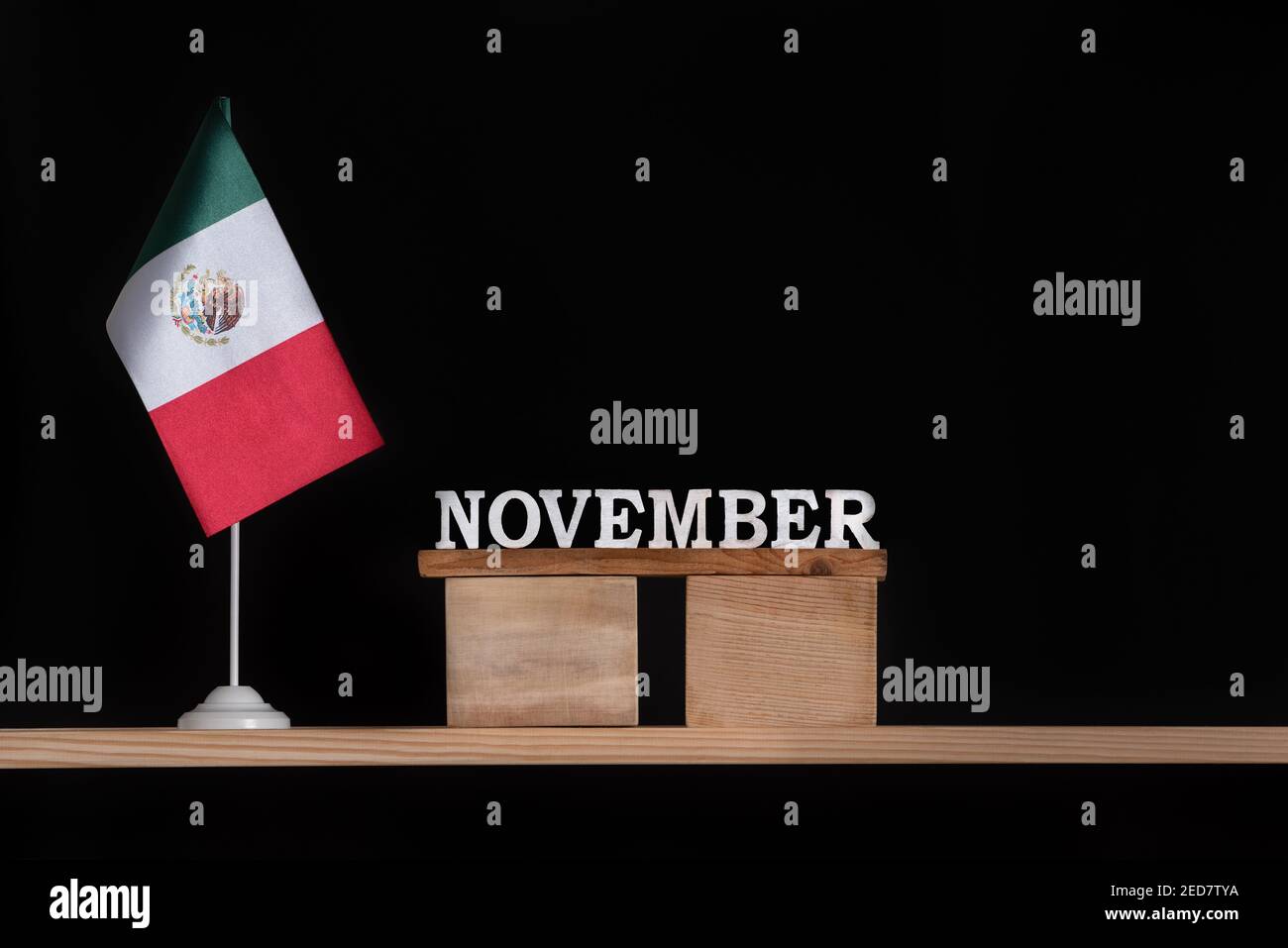 Wooden calendar of November with Mexico flag on black background. Holidays of Mexico in November. Stock Photo