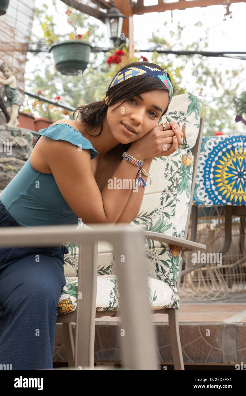 a short hair young woman sitting on a terrace, wears casual clothes and colorful accessories, lifestyle Stock Photo