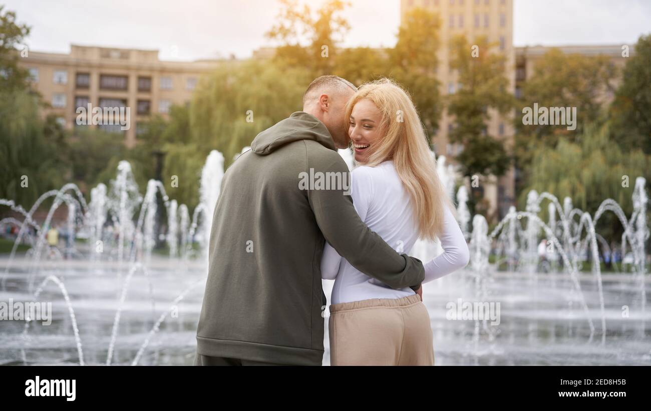 Couple in love walking outdoors park fountain Caucasian man woman walk outside after jogging dressed sport clothes Healthy livestyle Rear view Stock Photo