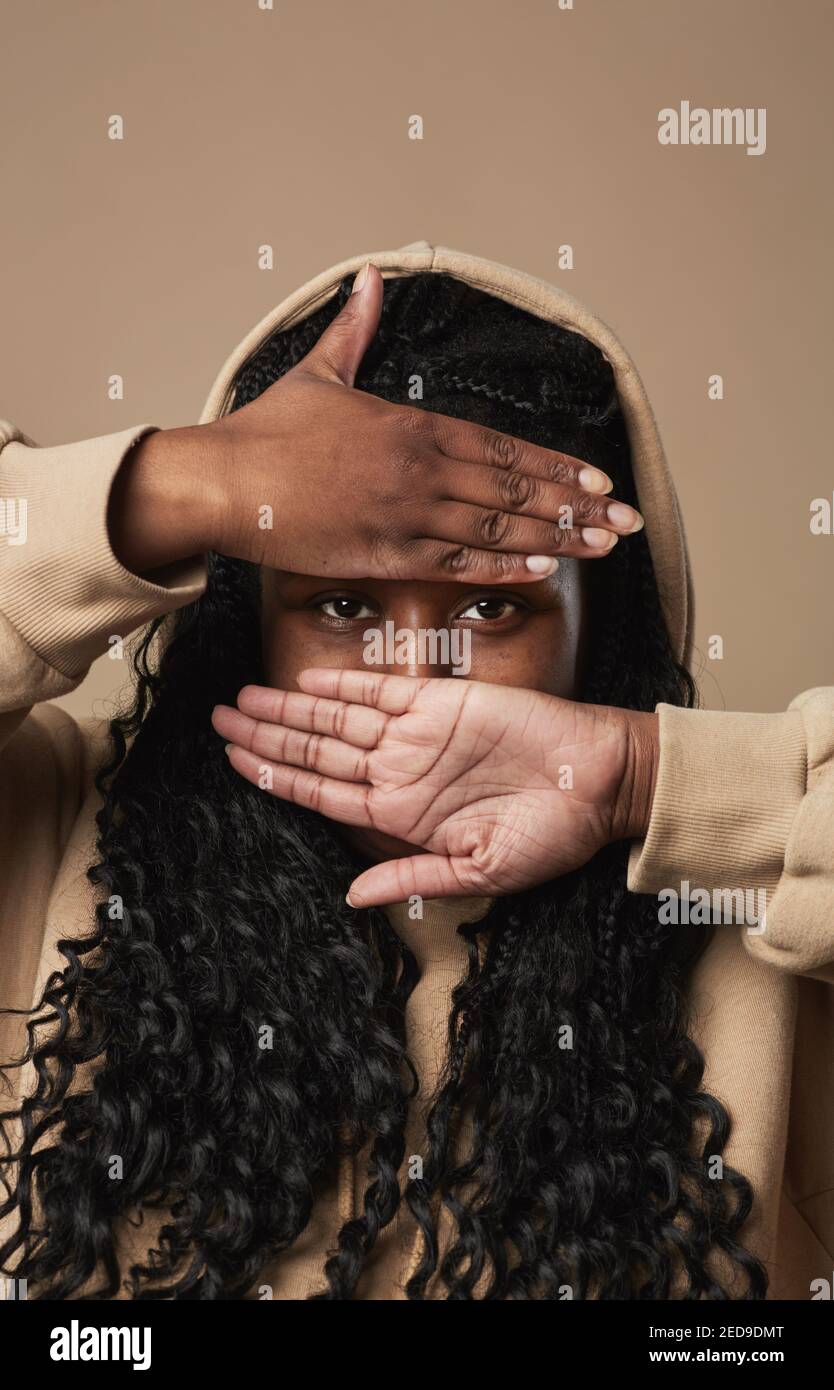 Vertical close up portrait of young African American woman hiding face ...