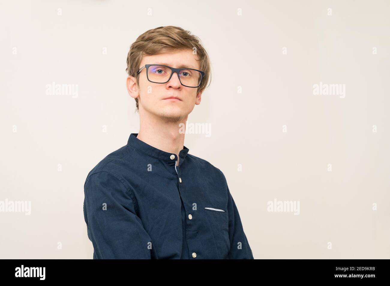 Portrait of handsome young blonde guy in blue shirt and glasses ...