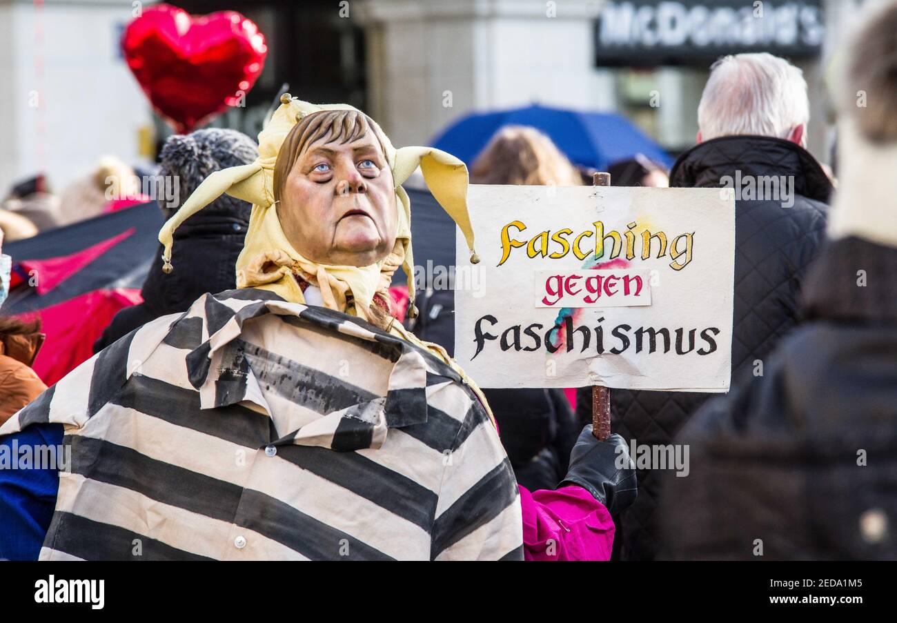 Munich, Bavaria, Germany. 14th Feb, 2021. A Merkel puppet next to a sign saying ''Carnival instead of fascism''. Both Chancellor Merkel and Minister-President Soeder are the main targets of hate from the Corona deniers. Exploiting both Valentine's Day and Fasching (Carnival), various groups of Corona deniers and anti-maskers under the label of Querdenken organized no fewer than a half dozen demos and motorcades in the city of Munich, Germany. After Trump's loss and the fracturing of the QAnon movement, the German group is seeking to reinvent itself, stepping up demonstrations, legal Stock Photo