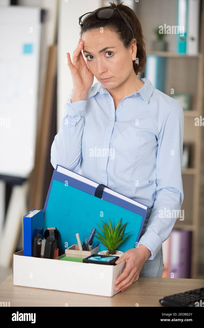 fired woman employee sitting with box outside the office Stock Photo